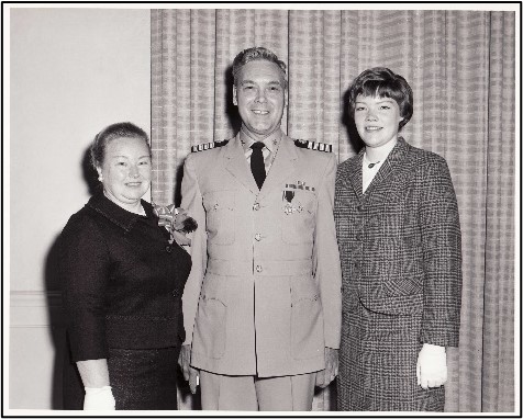 CAPT Taylor in uniform standing between two family members