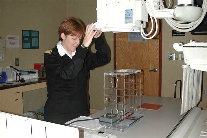 LCDR Grosch in uniform in a hospital room conducting a radiological survey